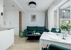 Ein stilvolles Wohnzimmer mit Essbereich, einem grünen Sofa und Blick ins Freie.
