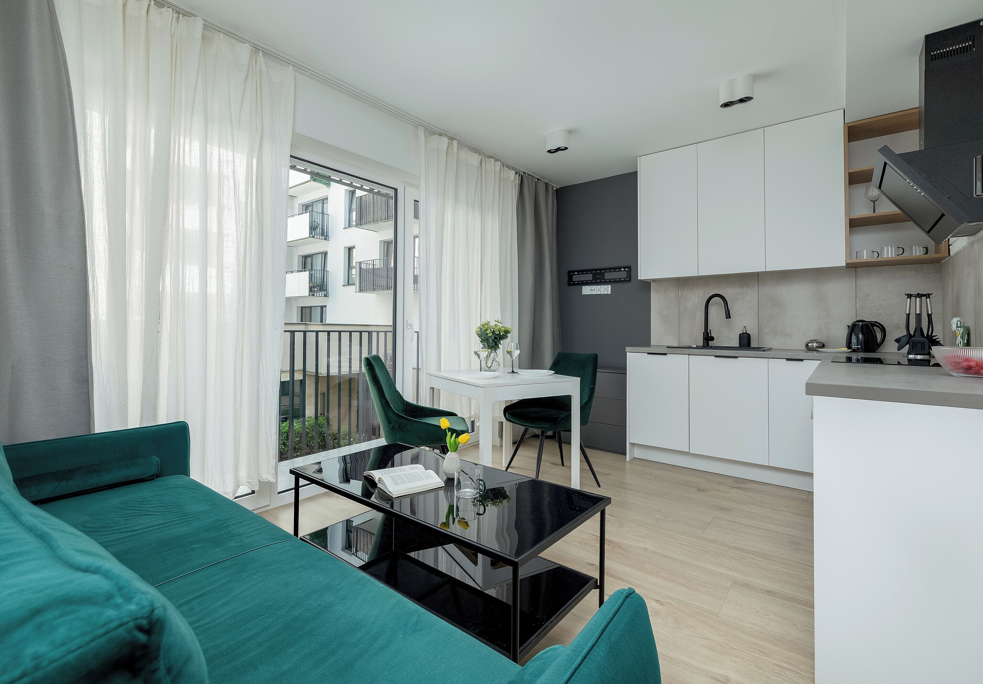 A modern apartment with a dining area, a kitchen, and a balcony with a view of the building.