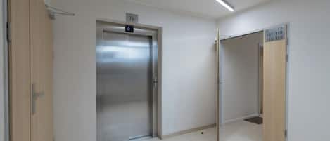 A clean, modern elevator with a digital display and a light fixture above.