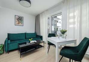 Ein modernes Wohnzimmer mit einem grünen Sofa, einem weißen Tisch und einem grünen Sessel.