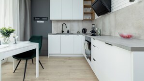 Moderni keittiö, jossa on valkoiset kaapit, musta hana ja sisäänrakennettu uuni.