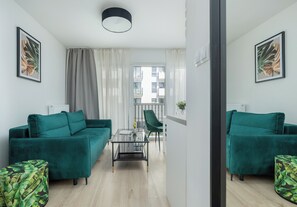 A modern living room with teal sofas, a glass coffee table, and a view to a balcony. - Szczecin Bronowicka Malachite Studio (Szczecin)