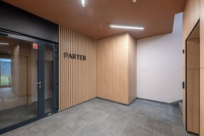 A modern interior with a wooden panel wall labeled 'PARTER' and a glass door entrance. - Pagi City Comfort Apartment with Garden (Lublin)