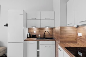 Een moderne keuken met witte kasten, een houten aanrechtblad en een roestvrijstalen spoelbak.