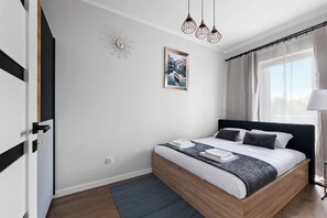 Een moderne slaapkamer met een bed, een wandklok, een lijst met een afbeelding en een raam met gordijnen.