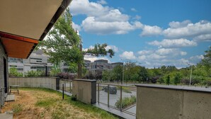 A view of a modern building with a concrete facade, a fenced outdoor area with grass, and a clear sky. - Pagi City Comfort Apartment with Garden (Lublin)