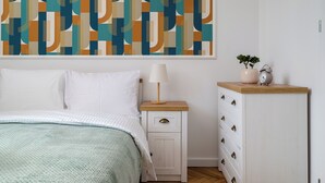 A bedroom with a bed, a nightstand, a dresser, and a wall with a geometric patterned wallpaper. - Nowy Świat Central Apartment (Warszawa)
