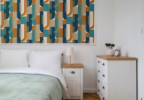 A bedroom with a bed, a nightstand, a dresser, and a wall with a geometric patterned wallpaper. - Nowy Świat Central Apartment (Warszawa)