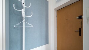 A room with a wooden door, a white wall, and a blue partition. - Nowy Świat Central Apartment (Warszawa)