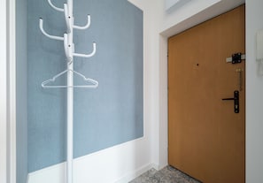 A room with a wooden door, a white wall, and a blue partition. - Nowy Świat Central Apartment (Warszawa)