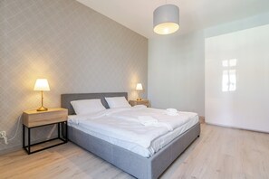 Een moderne slaapkamer met een bed, twee bedlampen en een groot raam.