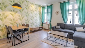 Ein Wohnzimmer mit Sofa, Couchtisch, Esstisch und Stühlen sowie einer Heizung.