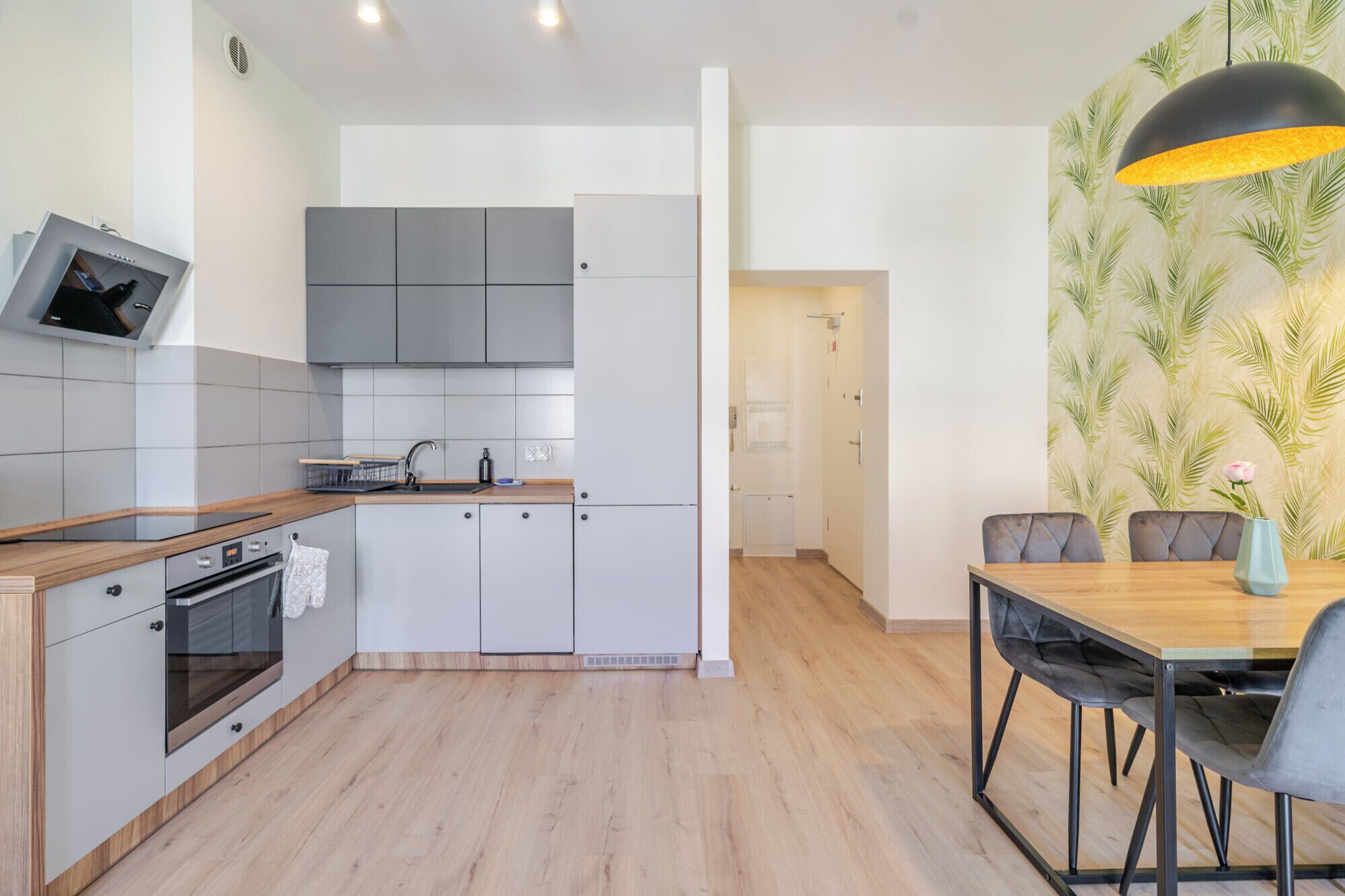 Une cuisine moderne avec des meubles gris, un plan de travail en bois et un four encastré.