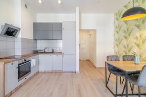 A modern kitchen with grey cabinets, a wooden countertop, and a built-in oven. - Mikołowska Silesian Charm Apartment (Katowice)