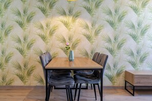 Een eetgedeelte met een houten tafel, vier stoelen en een vaas met een bloem.