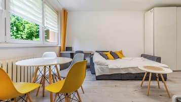 Een kleine kamer met een bed, een tafeltje en twee stoelen.