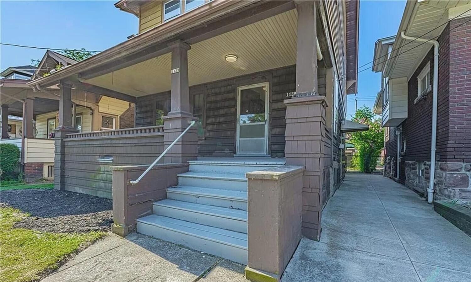 Un immeuble résidentiel doté d’un porche, d’un escalier et d’une porte d’entrée.