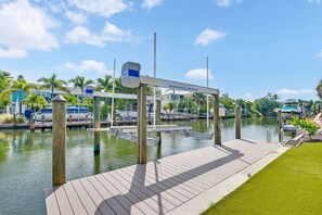 A marina with docked boats, a wooden pier, and a clear sky. - Pet Friendly Canal Home - Boat Lift + Paddleboards (Sarasota)