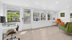 Ein modernes Zimmer mit großen Fenstern, einem Schreibtisch mit Computer und zwei Stühlen.