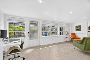 A modern room with large windows, a desk with a computer, and two chairs. - Pet Friendly Canal Home - Boat Lift + Paddleboards (Sarasota)