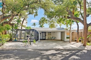 A house with a covered patio, a garage, and a bicycle parked outside. - Pet Friendly Canal Home - Boat Lift + Paddleboards (Sarasota)