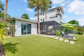 A modern two-story house with a covered outdoor seating area and a well-maintained lawn. - Pet Friendly Canal Home - Boat Lift + Paddleboards (Sarasota)