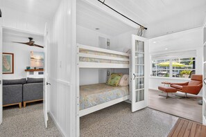 A room with a bunk bed, a sofa, a chair, and a window with a view of the outside. - Pet Friendly Canal Home - Boat Lift + Paddleboards (Sarasota)