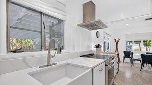 Eine moderne Küche mit Spüle, Edelstahlgeräten und einem Fenster mit Blick auf Grünflächen.