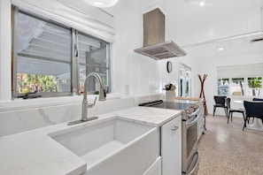 A modern kitchen with a built-in sink, stainless steel appliances, and a window overlooking greenery. - Pet Friendly Canal Home - Boat Lift + Paddleboards (Sarasota)