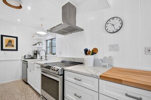 A modern kitchen with white cabinetry, a stainless steel range, a built-in oven, a wooden countertop, and a wall clock. - Pet Friendly Canal Home - Boat Lift + Paddleboards (Sarasota)