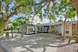 A covered outdoor seating area with a glass enclosure, a bicycle parked inside, and a mailbox. - Pet Friendly Canal Home - Boat Lift + Paddleboards (Sarasota)