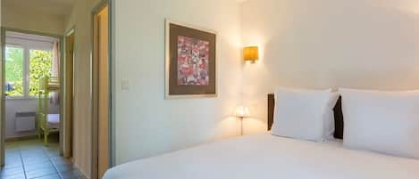 Una habitación de hotel con una cama, un cuadro, una lámpara y vistas a un balcón.