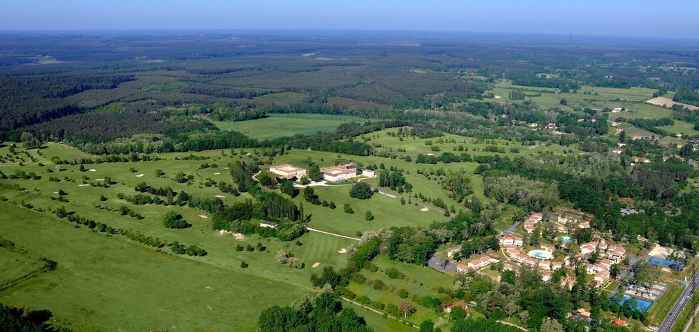 Un paysage rural avec un vaste domaine comprenant plusieurs bâtiments, de vastes champs et une piscine.