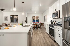A modern kitchen with white cabinetry, stainless steel appliances, and a central island with seating. - Skyline 3 Homes Retreat, Private Swim Spas, SLP 48 (Washington)