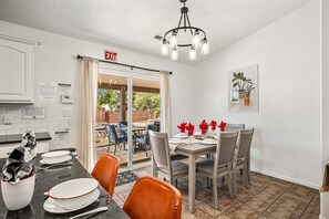 A dining area with a table set for four, a chandelier, and an exit sign above a door. - 3819, Private Pool, Private Spa, BBQ, Outdoor Fire Pit, Xbox 1 (Hurricane)