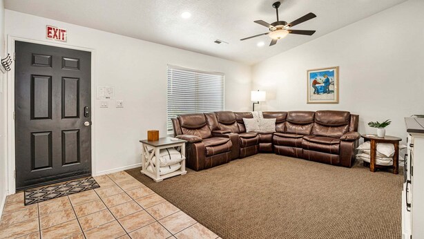 A living room with a sectional sofa, a ceiling fan, a door with an exit sign, and a small table with a lamp. - 3819, Private Pool, Private Spa, BBQ, Outdoor Fire Pit, Xbox 1 (Hurricane)