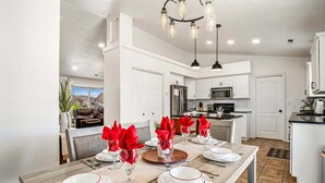A modern kitchen with white cabinets, stainless steel appliances, and a dining area set for a meal. - 3819, Private Pool, Private Spa, BBQ, Outdoor Fire Pit, Xbox 1 (Hurricane)