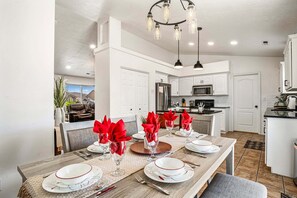 A modern kitchen with white cabinets, stainless steel appliances, and a dining area set for a meal. - 3819, Private Pool, Private Spa, BBQ, Outdoor Fire Pit, Xbox 1 (Hurricane)