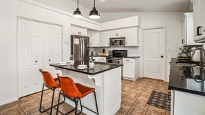 A modern kitchen with white cabinetry, stainless steel appliances, and a central island with bar stools. - 3819, Private Pool, Private Spa, BBQ, Outdoor Fire Pit, Xbox 1 (Hurricane)
