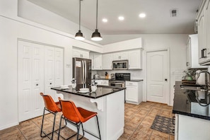 A modern kitchen with white cabinetry, stainless steel appliances, and a central island with bar stools. - 3819, Private Pool, Private Spa, BBQ, Outdoor Fire Pit, Xbox 1 (Hurricane)