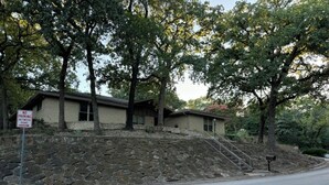 A two-story house with a stone retaining wall and a metal staircase leading to the entrance. - Spacious 4-bedroom house near DFW (Euless)