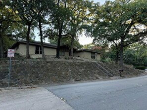 A two-story house with a stone retaining wall and a metal staircase leading to the entrance. - Spacious 4-bedroom house near DFW (Euless)