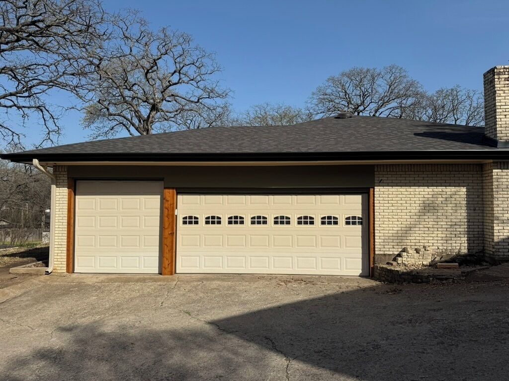 A two-car garage attached to a brick house with a sloped roof.