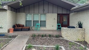 A house with a covered porch, a brick exterior, a front door, and a seating area with a sofa and chairs. - Spacious 4-bedroom house near DFW (Euless)