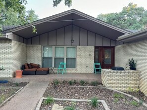 A house with a covered porch, a brick exterior, a front door, and a seating area with a sofa and chairs. - Spacious 4-bedroom house near DFW (Euless)