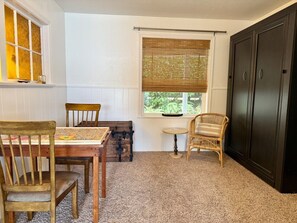 A room with a dining table, two chairs, a small round table, and a window with blinds.
