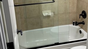 A bathroom with a glass-enclosed shower, a white bathtub, and a toilet. - Foothills gem! (Tucson)