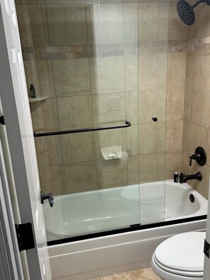 Ein Badezimmer mit Duschkabine, freistehender Badewanne und Toilette.