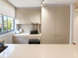 A modern kitchen with a built-in oven, a stovetop, and a window providing a view of the outside.