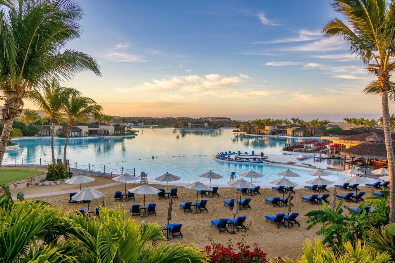 A resort with multiple swimming pools, sun loungers, and palm trees.